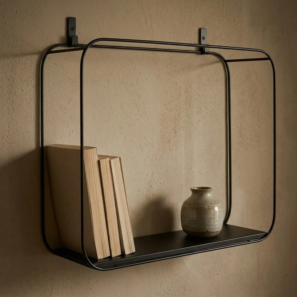 Gros plan sur la grande étagère géométrique : cadre en fil d'acier noir, pattes de fixation et plateau noir, avec livres et vase en grès